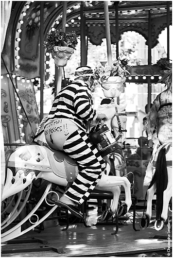 Photo humoristique d'un jeune homme portant un d&eacute;guisement de bagnard sur un man&egrave;ge de chevaux de bois pour l'enterrement de sa vie de gar&ccedil;on. &copy; juillet 2010 Christophe Letellier tous droits r&eacute;serv&eacute;s. 
