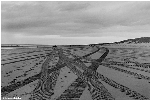 Photo noir et blanc de la galerie "Entre ciel et terre". Rayons lumineux du soleil filtrés par les nuages sur la plage de Kairon (Manche) à marée basse. © Août 2001 Christophe Letellier, tous droits réservés. Pour revenir à la galerie, cliquez sur la photo.