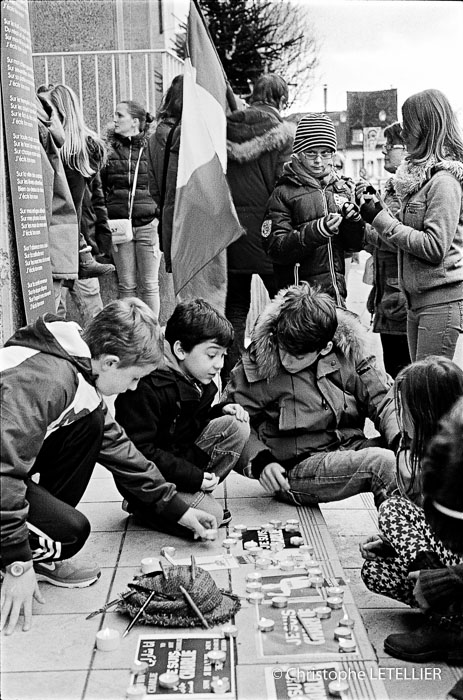 Photo en noir et blanc de jeunes enfants allumant une bougie d'espoir durant la marche organisée à Gisors suite au massacre de l'attaque terroriste contre l'hebdommadaire Charlie Hebdo © 2015 Christophe Letellier all rights reserved. 