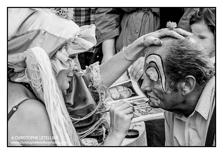 Photo noir et blanc "visage de clown". A Granville, une maquilleuse professionnelle effectue,sous le regard amusé des enfants et des touristes, un maquillage de clown sur le visage d'un vieil homme.© 2010 Christophe Letellier tous droits réservés. Pour revenir à la galerie, cliquez sur la photo.